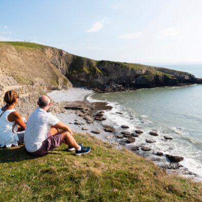 A beautiful afternoon view of two people overlooking Southerndown beach and ocean at high tide near to Wagon House Holiday Cottages. Wagon House Holiday Cottages are in the beautiful Vale of Glamorgan, Wales. The converted holiday cottages are situated in a quiet village only 10 minutes walk from the sea.